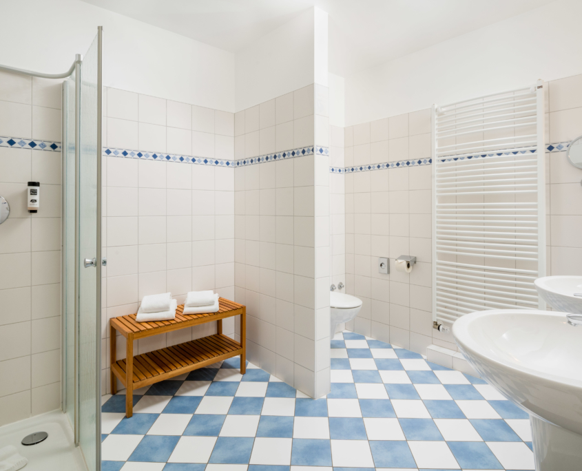 Großzügiges Badezimmer einer Suite im Parkhotel Wangerooge mit großer Dusche, zwei Waschbecken, Handtuchwärmer und Sitzbank