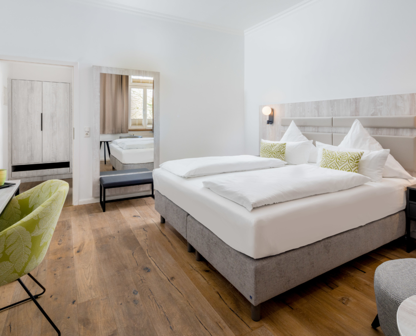 Geräumiges Doppelzimmer im Parkhotel Wangerooge mit großem Wandpiegel, Schreibtisch, Kleiderschrank und Sessel mit Beistelltisch