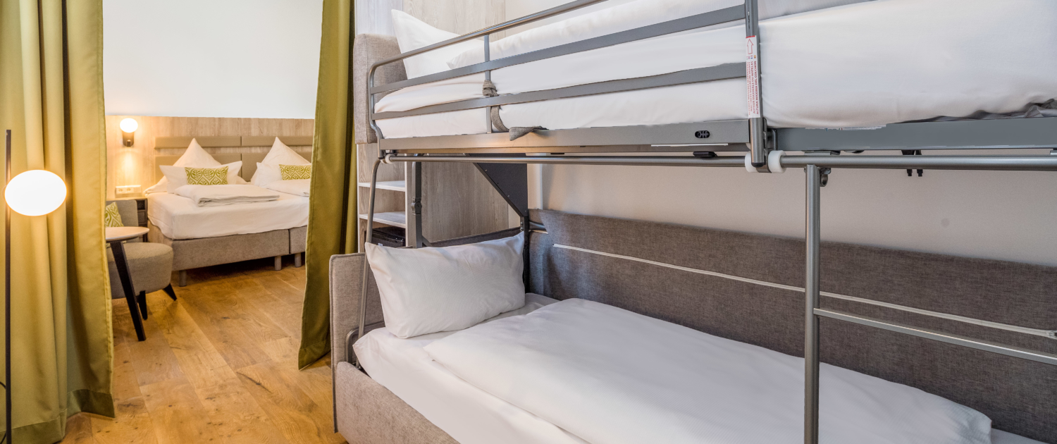 Familienzimmer im Parkhotel Wangerooge mit Doppelbett und einem durch einen Vorhang abgetrennten Bereich mit Etagenbett