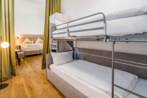 Familienzimmer im Parkhotel Wangerooge mit Doppelbett und einem durch einen Vorhang abgetrennten Bereich mit Etagenbett