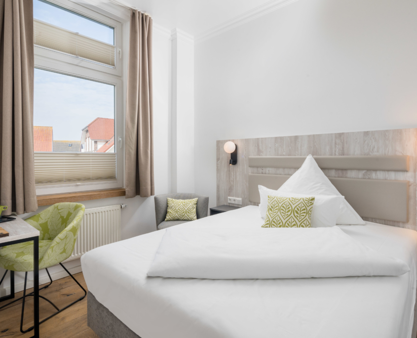 Helles, modern eingerichtetes Einzelzimmer im Parkhotel Wangerooge mit Schreibtisch, Sessel und gemachtem Bett