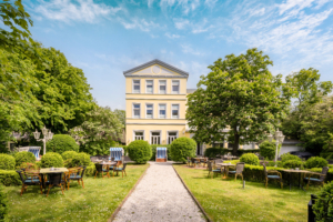Außenansicht des historischen Parkhotel Wangerooge mit weitläufigem Garten, Sitzgruppen und Strandkörben